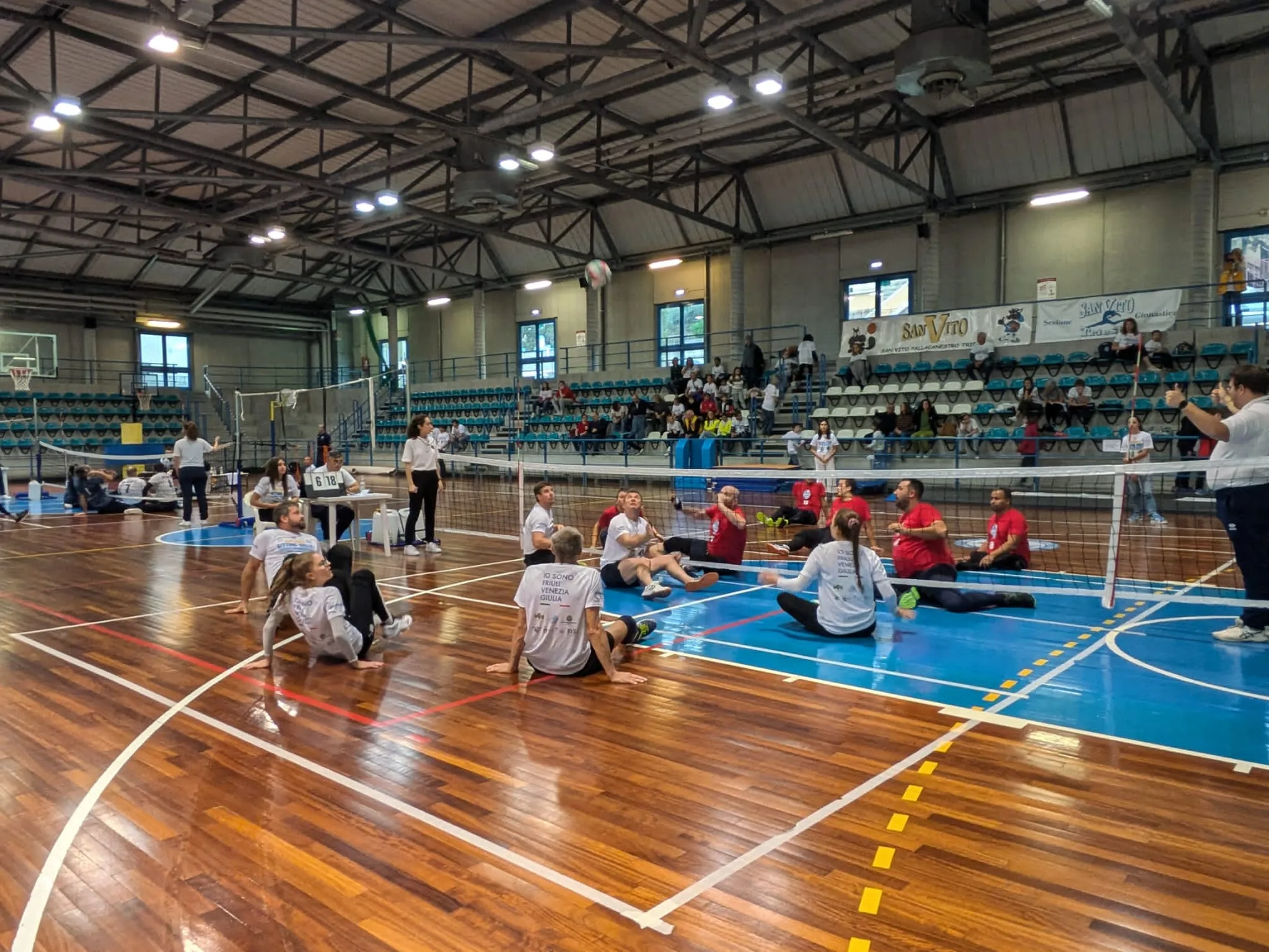 Die spieler sitzen am Spielfeld, der Volleyball in der Luft über ihnen